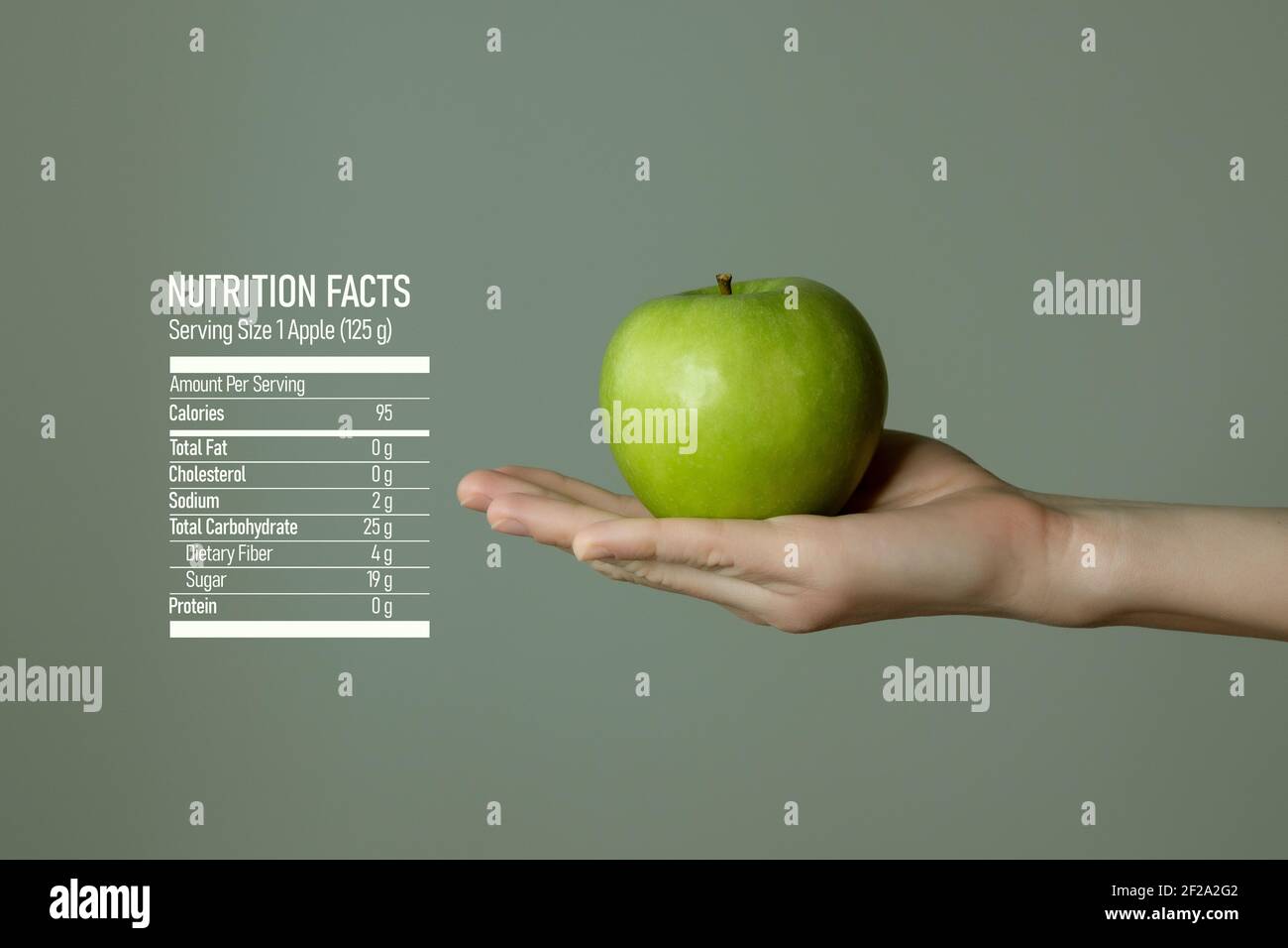 Frau`s Hand hält grünen Apfel, Ernährung Fakten auf grauem Hintergrund. Diätetische Lebensmittel und Vitamine Konzeptvorlage für Produktwerbung. Stockfoto